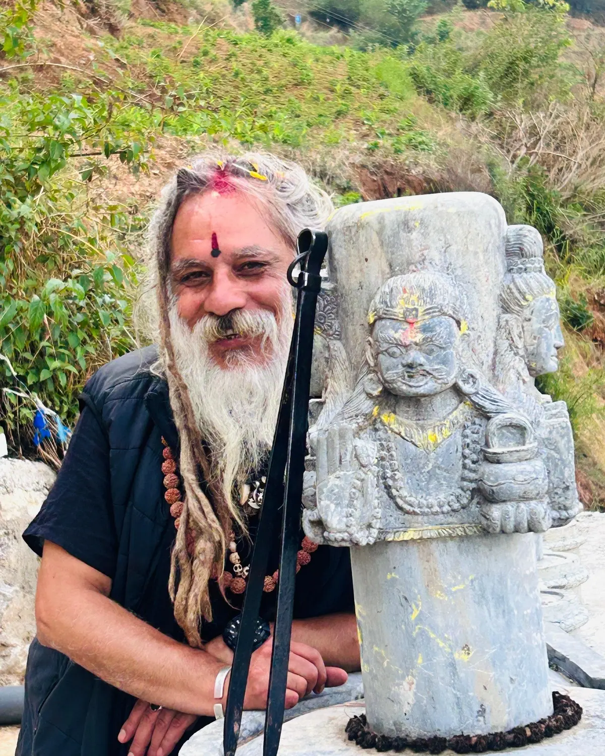 Baba beside a Bhairava statue in the Kathmandu Valley
